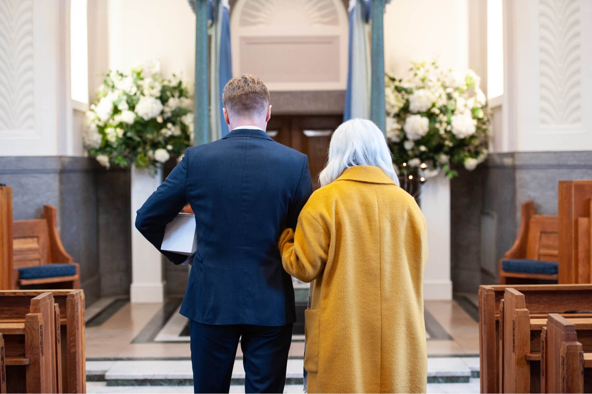 A celebrant walking into a chapel beside a family member
